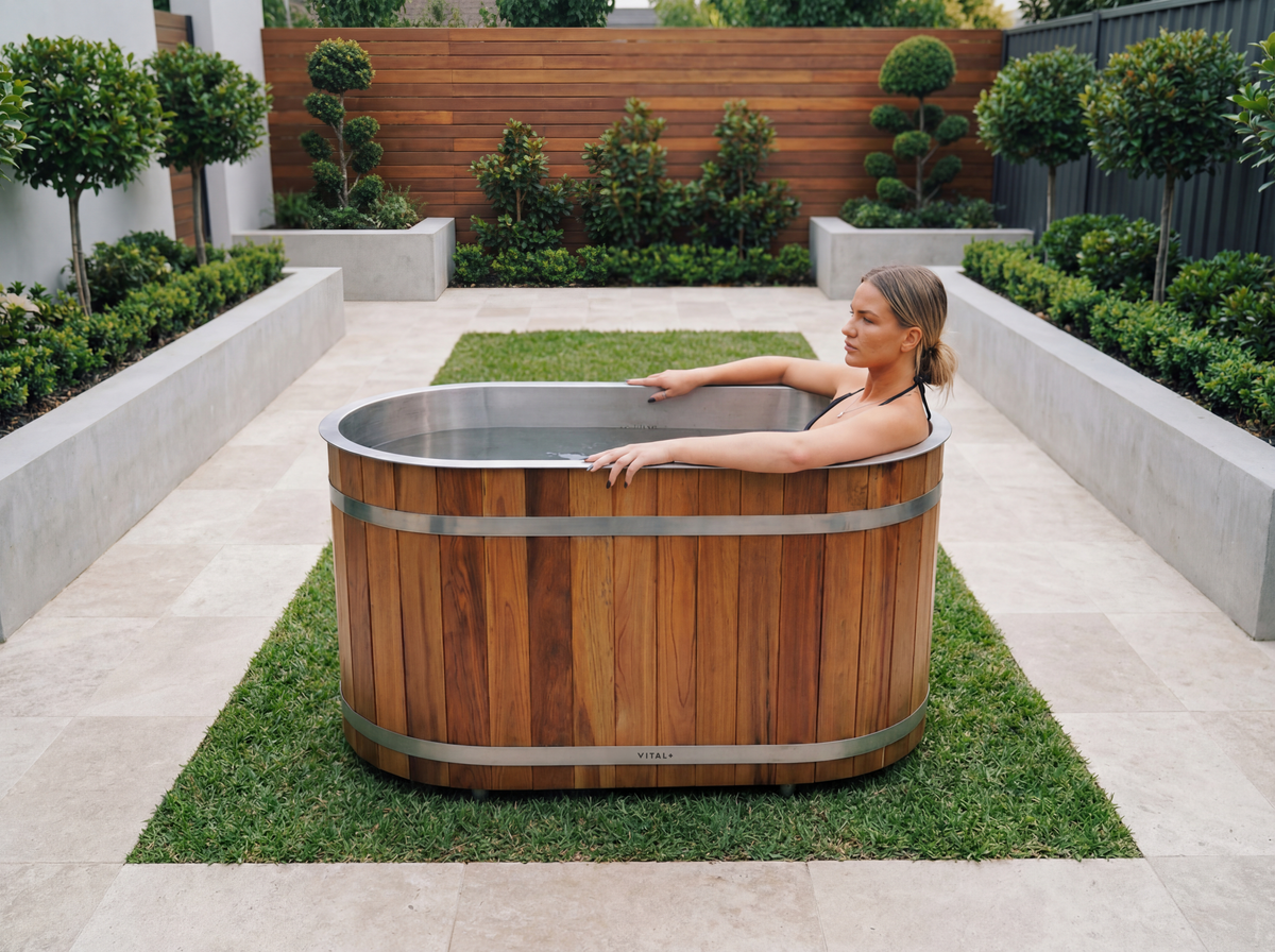 Woman relaxing in a red solo cedar tub outdoors with a garden background