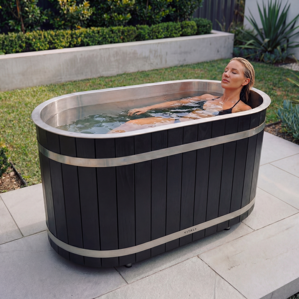 Woman relaxing in a black solo cedar tub outdoors